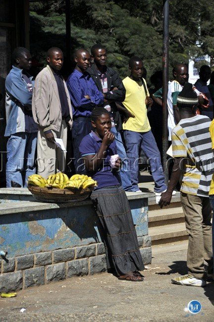 A woman who sells bananas takes off some time from her busy work to sample some ice cream at the Lusaka main post office