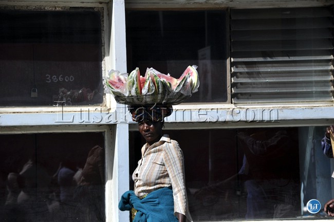 A woman who sells water melons in pieces searches for along Cairo road in Lusaka