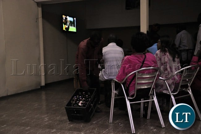 A bar attendant passes some drinks around during the televising of the Zambia Bukina Faso match at a certain Pub in Lusaka