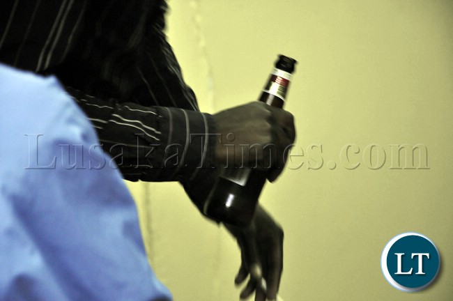 A soccer fan holds a bottle of Castle lager during the televising of the Zambia Bukina Faso match in Lusaka.