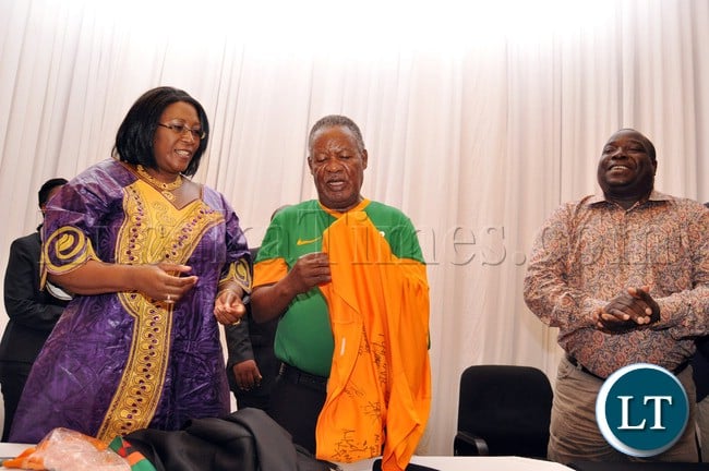 President Sata trying to wear the Chipolopolo Jersey by First Lady Dr Christine Kaseba as Sports minister Chishimba Kambwili looks on