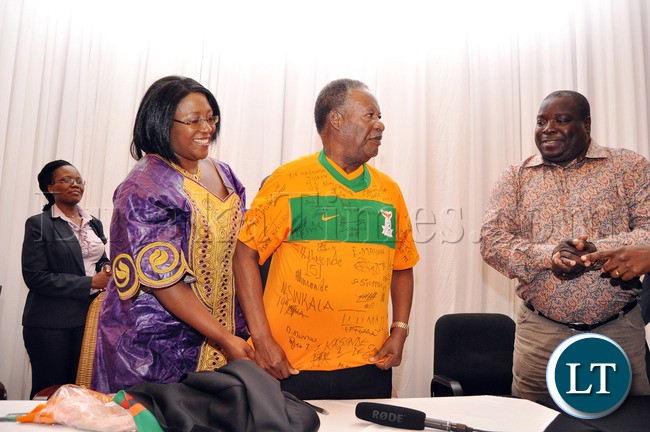 President Sata being helped to put on a Chipolopolo Jersey by First Lady Dr Christine Kaseba as Sports minister Chishimba Kambwili looks on