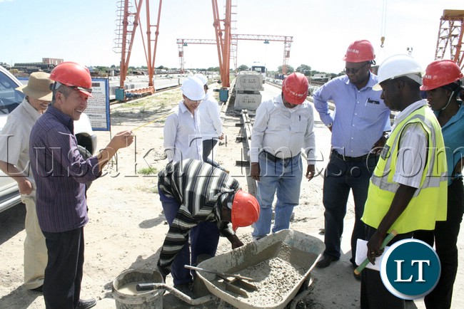 (Mongu-Kalabo Road) Western Province Permanent Secretary Emmanuel Mwamba third from (r) looking carefully how they mix the cement and stones during the tour of the AVIC bridge department at their comp site of Mongu–Kalabo