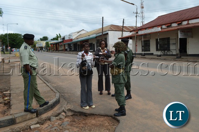 Police Officers check the identity cards of Zambezi FM reporters Angela Hanunka (far right) and Kawewa Kabika (middle) outside court premises in Livingstone