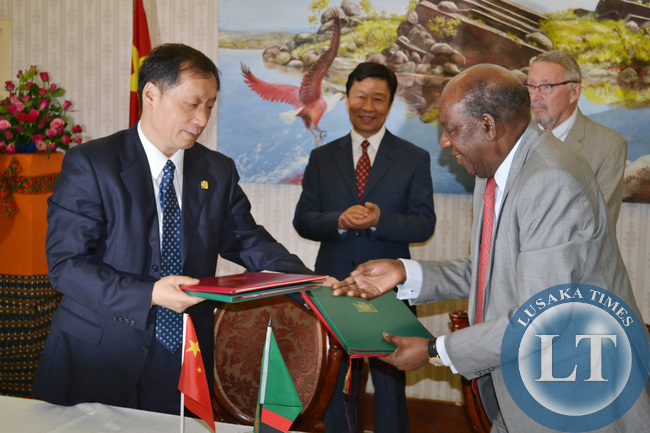 Finance Minister Alexander Chikwanda exchanges folders with Chinese Vice Minister of Commerce Li Jinzao (left) after signing various agreements in the presence of Vice President Guy Scott and Chinese Vice President Li Yuanchao (second from left) look on at Government House in Lusaka