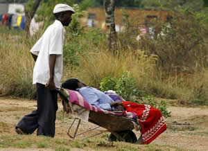 cholera1 A man pushes his relative in a wheelbarrow to a Cholera Polyclinic, where victims of cholera are being treated in Harare, Zimbabwe. by AFP