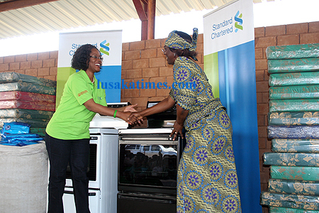 Stanchart managing director Mizinga Melu (l) greets Village of Hope Board chairperson, Agness Daka after donating an assortment of household goods in Kitwe