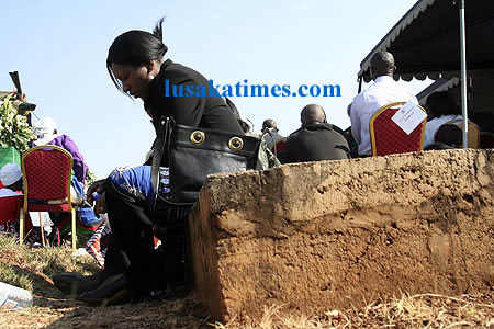 A mourner resting on a tombstone during the burial of the late Mwanakatwe in at old Leopards Hill cemetry