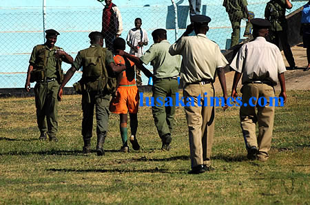 Police officers apprehend an soccer hooligan at Nkoloma stadium