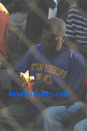 A soccer fan mixing a soft drink and Tujilijili (a strong alcoholic drink) during a match at Nkoloma stadium on Saturday