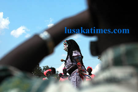 A photographer taking pictures of a female nyau dancer