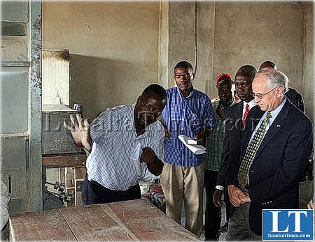 Director for Diocese Mongu Development Centre Eugene Mubuyaeta show United States Ambassador to Zambia Donald Booth hastes of rice during the tour in Mongu