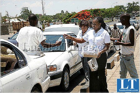 Eco Bank Zambia members of staff distribute free bottled water to motorists queuing up for petrol at the BP filling station at Arcades shopping center on Great East road in Lusaka