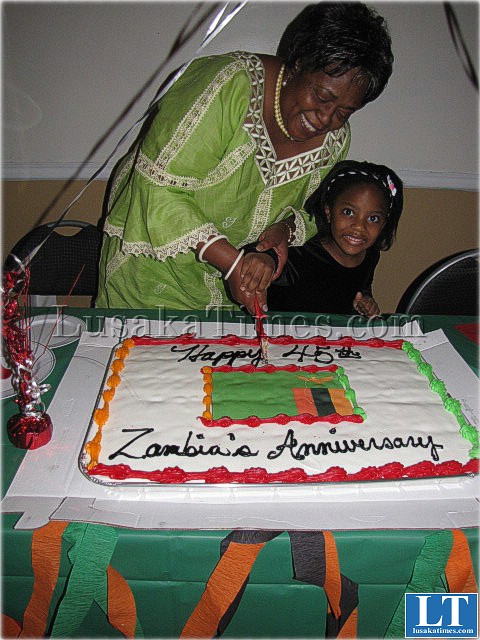 Zambia's Ambassador at a Zambian Independence Day celebration in Baltimore cutting a ckae with young Jermima UdosenIMG_0956
