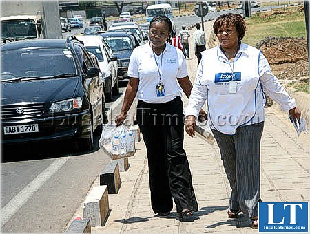 Eco Bank Zambia members of staff distribute free bottled water to motorists queuing up for petrol at the BP filling station at Arcades shopping center on Great East road in Lusaka