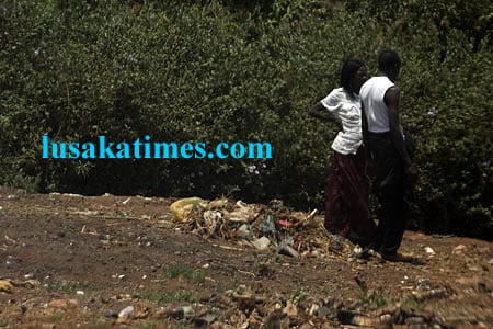 A couple chatting oblivious of the dump site behind them despite efforts by the keep Zambia clean campaign in Lusaka