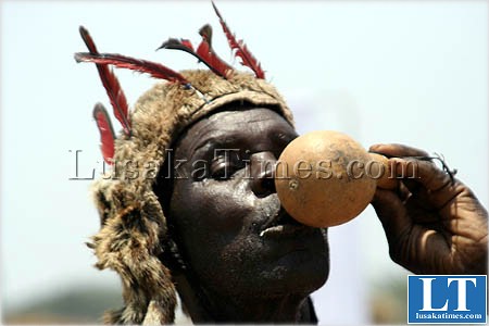 A traditional dancer cools off with the traditional brew after a dance