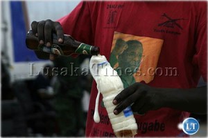 A ZANU-PF cadre pours Mosi Lager into a mineral water bottle because he was not allowed to take the Zambian Breweries Group mosi bottle away in Chirundu