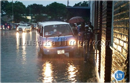 Mini bus sharing sidewalk with pedestrians because middle of road is flooded