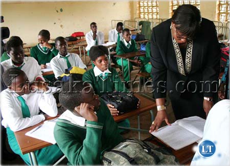 File: Education Minister Dora Siliya checks a book of a pupil when she toured Lusakasa Basic School