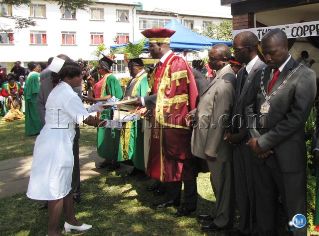 Copperbelt minister Davis Mwila hands over a certificate to one of the midwives at the graduation ceremony in Kitwe. Standing on his left is provincial medical officer Chandwa Ng'amba, district commissioner Elias Kamanga and Kitwe mayor Chileshe Bweupe