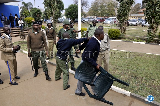 Police officers manhandle a UPND cadre who had carried the chair for party president Hakainde Hichilema