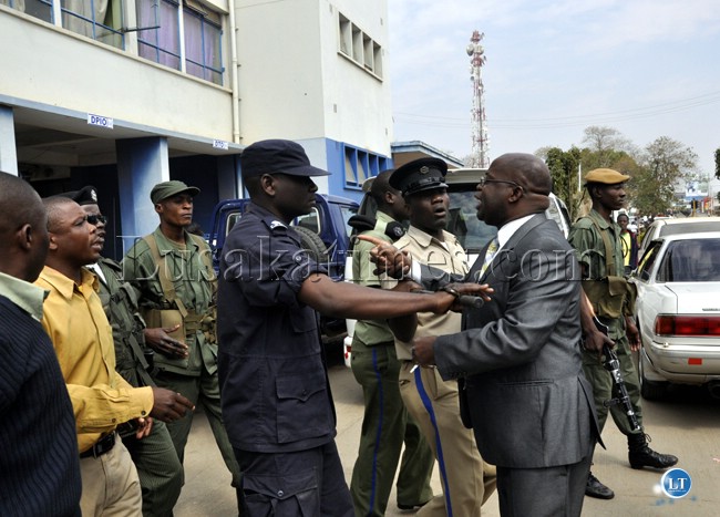 Police officers push Zambezi West Member of Parliament Charles Kakoma out of the Lusaka Central Police Station.