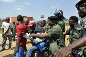 Police officers push a PF youth who wanted to start a fight with UPND cadres at the Lusaka magistrate court
