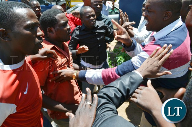 Police officers (right) try to control suspected riotous UPND cadres at Woodlands police station in Lusaka