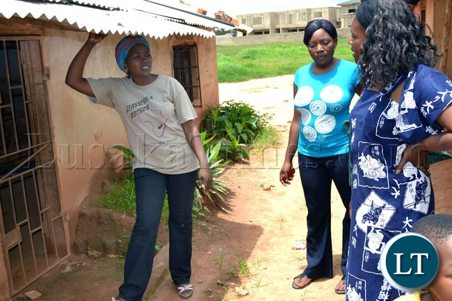 The classrom block's roof is too low for the average person as one has to stoop to stand under the assemblage of ricky corrugated iron sheets as demonstrated by Mango groove head teacher.