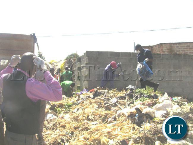 Mkushi DC Christopher Chibuye(right with refuse bag), joins Council workers at a garbage site in Itala compound