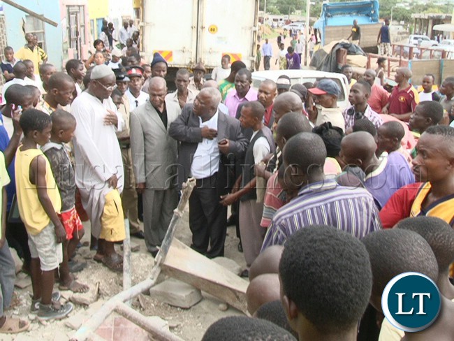 Northern Province Minister Gerry Chanda (centre) and Mpulungu Member of Parliament Freedom Sikazwe (grew suilt) at the accident scene of the truck Registration Number ABV9630 which left 6 people dead and 24 injured after the driver lost control and hit in a stationed vehicle and building belonging to Map business in Mpulungu