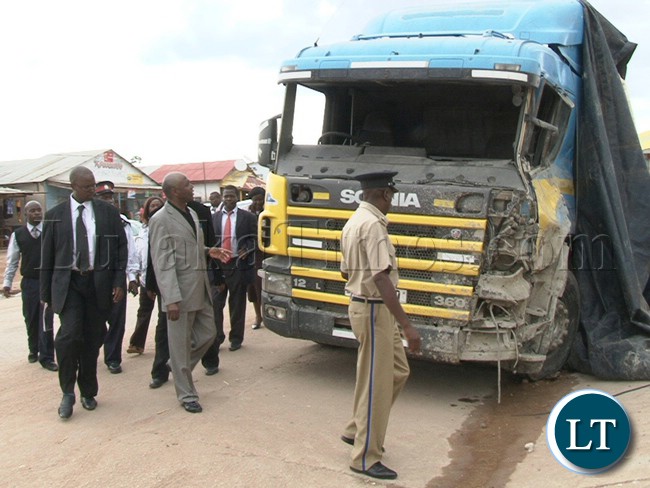 Northern Province Minister Gerry Chanda (centre) and Mpulungu Member of Parliament Freedom Sikazwe (grew suilt) having a glimpse of the truck Registration Number ABV9630 which left 6 people dead and 24 injured after the driver lost control and hit in a stationed vehicle and building belonging to Map business in Mpulungu