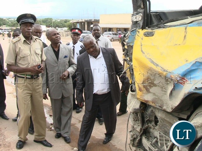 Northern Province Minister Gerry Chanda (centre) and Mpulungu Member of Parliament Freedom Sikazwe (grew suilt) having a glimpse of the truck Registration Number ABV9630 which left 6 people dead and 24 injured after the driver lost control and hit in a stationed vehicle and building belonging to Map business in Mpulungu