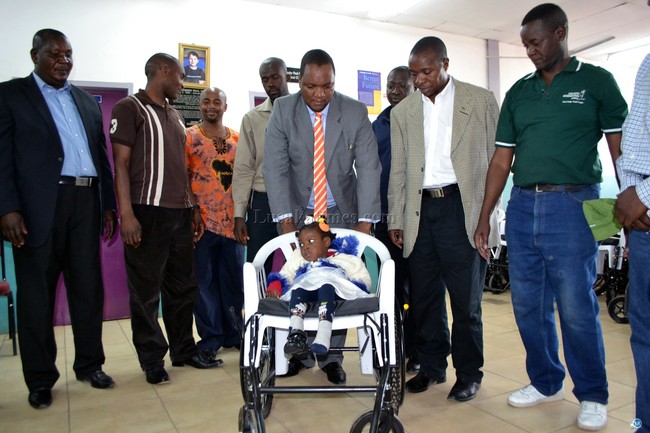 Matero Member of Parliament Miles Sampa pushes a child on one of the 60 wheel chairs donated by Children International which he handed over to children with disabilities in George Township in Lusaka recently