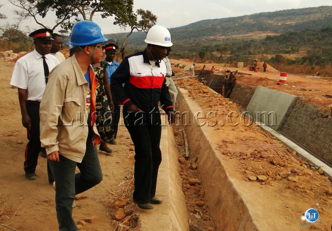 NORTHERN Provincial Minister Obious Chisala (right) inspecting a water canal at Lunzuwa Hydro-Power station in Mpulungu district yesterday with China National Electric Engineering Company (CNEEC)’s Assistant Manager Cheng Yu Hong in a blue helmet.