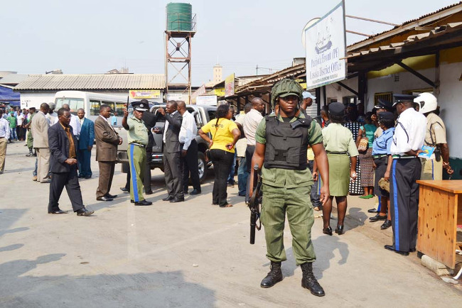 DEPUTY Inspector-General of Police Solomon Jere issues instructions to plain-clothed officers as another armed officer keeps vigil at the Patriotic Front (PF) Lusaka District Office