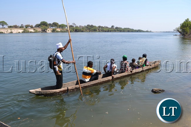 Gift Chingimbu balances a baby of one of his passengers on his back as he paddles away his canoe across the Zambezi River for the Likumbi Lyamize traditional ceremony.