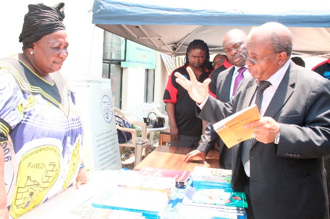 FAWEZA Mongu District Charperson Limpona Nakwebwa (l) listens to Education Minister Dr. John Phiri (r) the books as Western Province Ps Amos Malupenga looks on during the Launch of the National Libraries Week at Mongu Librabry in Mongu Western Province