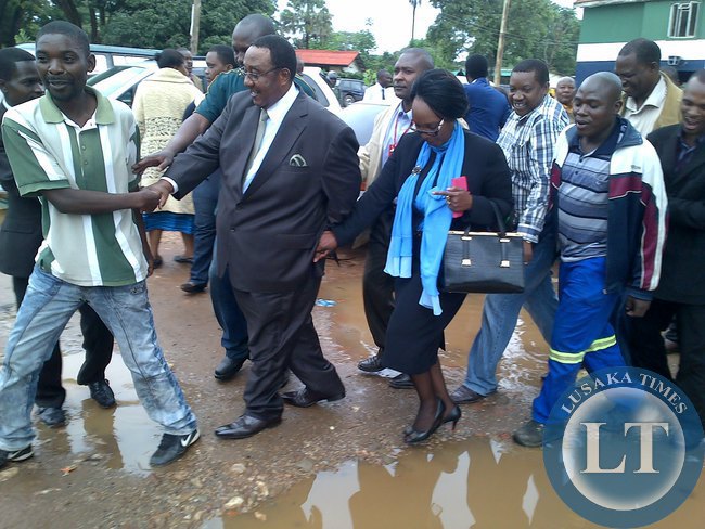 Former Defence minister Geoffrey Mwamba and his wife make their way through the muddy potholes at Woodlands police station
