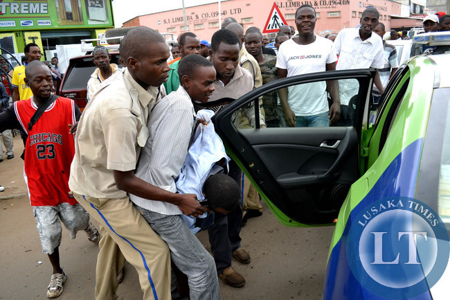 Police officers bundle a minibus driver into the Road Transport and Safety Agency (RTSA) patrol car after police officers were involved in a high speech chase with the minibus driver along Freedom Way in Lusaka in Lusaka
