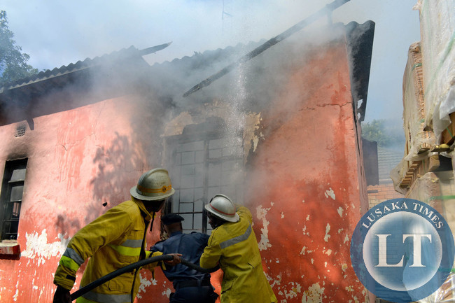 International Women's Day turned tragic for a Rhodespark family in Lusaka when a fire burned their house to ashes. Above, firefighters fight the inferno as the roof curved in