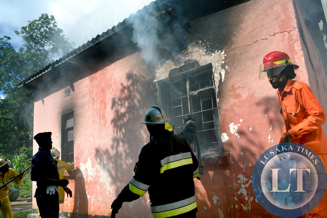 International Women's Day turned tragic for a Rhodespark family in Lusaka when a fire burned their house to ashes. Above, firefighters fight the inferno as the roof curved in
