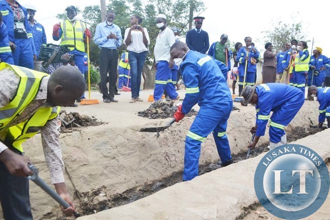 USAKA Province Permanent Secretary Wamunyima Muwana (with raised leg), Lusaka District Commissioner Ashell Kampengele (in blue work suit, wearing hat) and Chawama Ward two councilor Potipher Tembo (in grey trousers) when they joined female Road Development Agency female members of staff to clean drainage facilities in Chawama Township yesterday ahead of International Women's Day