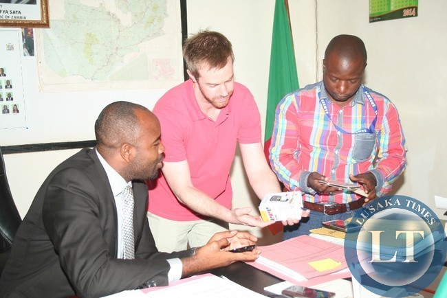 SAMSUNG Field Engineer from South Africa, Richard Lawrenson (c) and Samsung Zambia representative, Jonathan Nsama ( r ), show Eastern Province Minister, Malozo Sichone, some counterfeit Samsung mobile phones at his office in Chipata