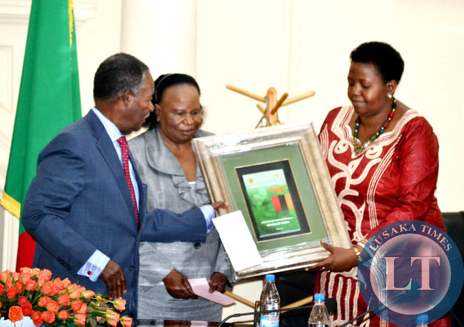President Michael Sata receives a gift from African Peer Review Mechanism (APRM) eminent person Ambassador Fatuma Ndangiza Nyrirakobwa (right) as Acting Chief Justice Lombe Chibesakunda (centre) looks on during the launch of the APRM report at State House in Lusaka