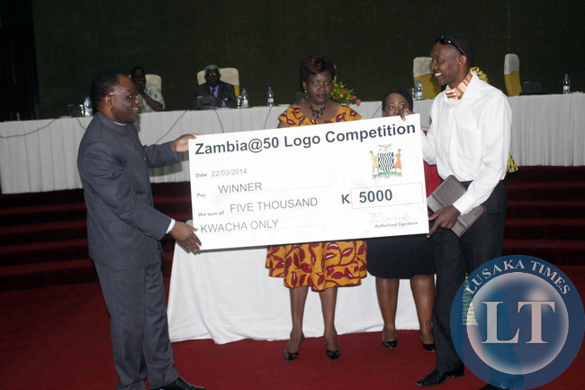 Secretary to Cabinet Roland Msiska (left) presents a dummy check to Angelus Mubita, the man who designed Zambia's Golden Jubilee logo.