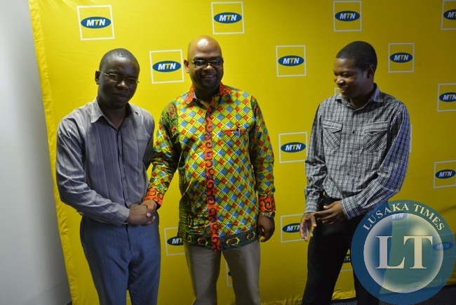 MTN Chiefs Sales and Distribution Officer Amon Jere having a ward with Emmanuel Sakala who developed called Zed Health Facilite whilst Joe Phiri developer Sherlock application is looking on during the launch of second phase of MTN application at MTN offices
