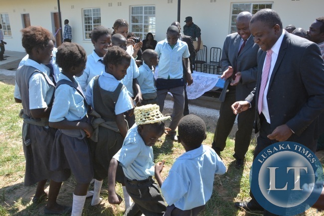 Deputy Minister in the office of the vice President Davis Mwango and Chibombo District Commissioner Felix Mangwato joining Namayani pupils in celebrating the handover of the classroom and the house during the handover of the 4 school built in Chibombo District at Namayani Primary School