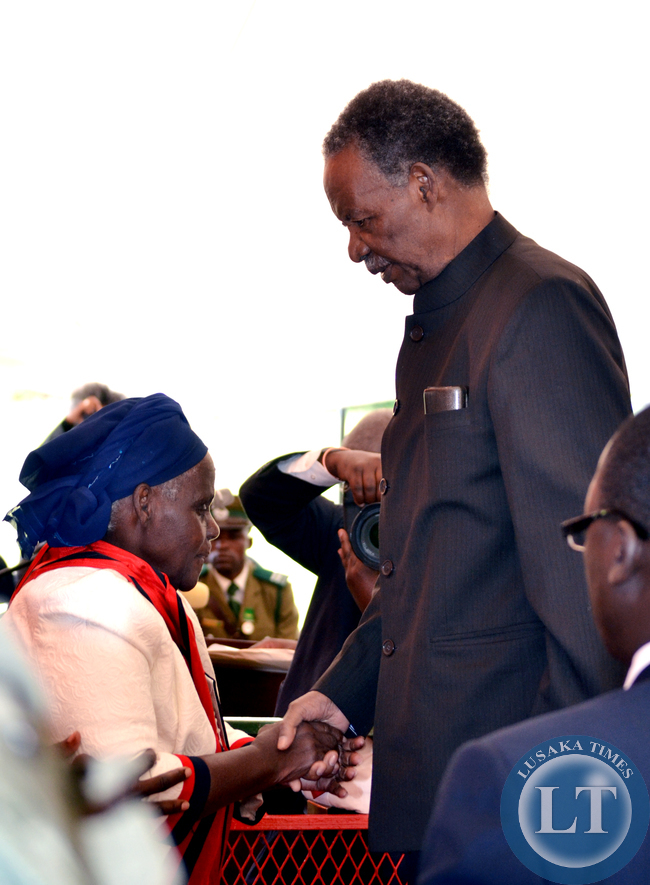 President Michael Sata shakes hands with Doris Chimanyika after honouring her with the Grand Commander of the Companion Order of Freedom during the investiture ceremony at State House in Lusaka